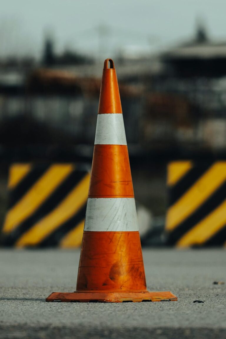 Close-up of an orange traffic cone on a city street, symbolizing road safety.